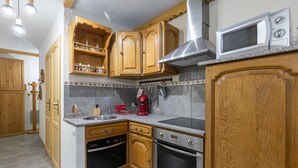 Eine Küche mit Holzausstattung, einer Edelstahl-Dunstabzugshaube, einer Mikrowelle und einer roten Kaffeemaschine.