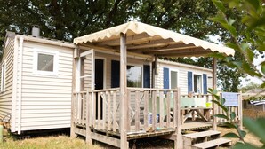 A mobile home with a wooden deck and a covered porch. - Bréhadour - Confort 3 TV - 7p (8) (Guérande)