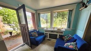 Une pièce chaleureuse avec deux fauteuils bleus, une petite table et une fenêtre avec des rideaux.