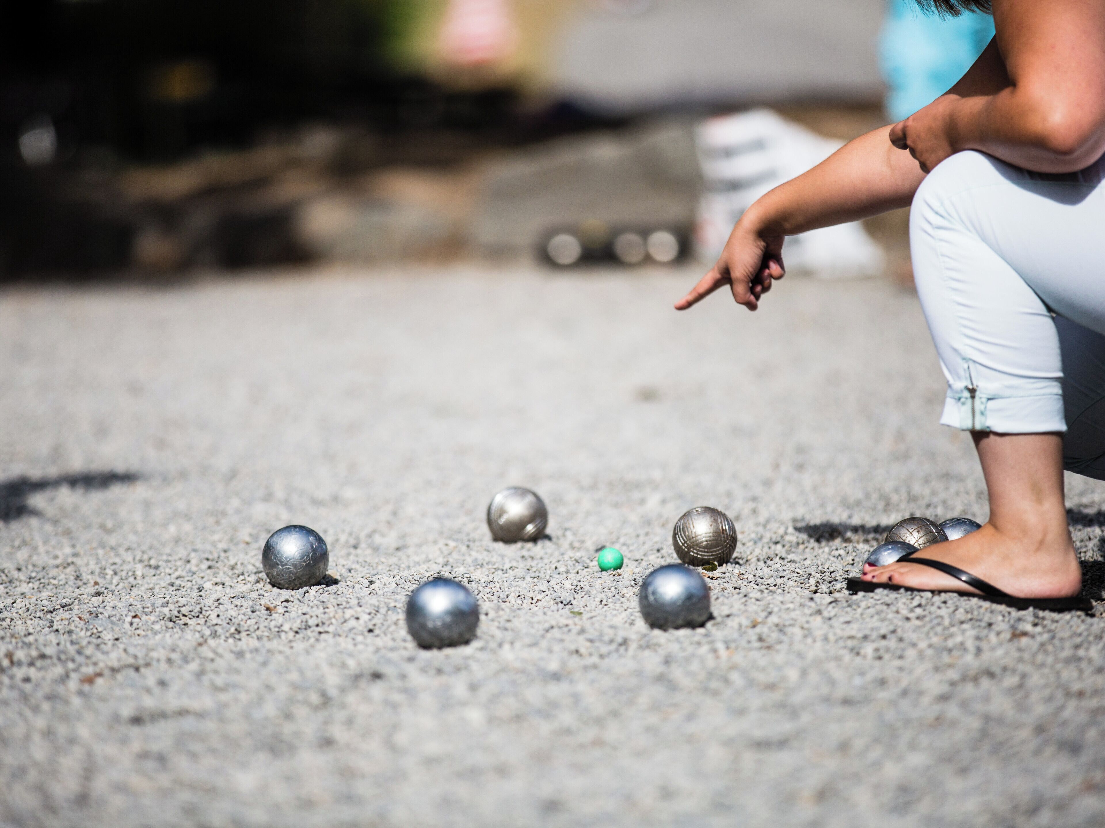 En person leger med metalbolde på en grusoverflade.