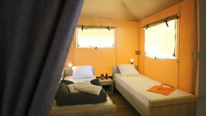 Una habitación compacta con dos camas, una mesita pequeña y una ventana con cortinas.