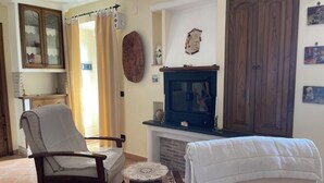 Un salon avec une cheminée, un meuble en bois, un fauteuil et une petite table ronde.