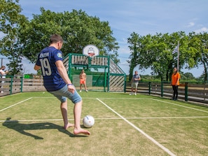 Een sportveld met een basketbalveld en een voetbal.