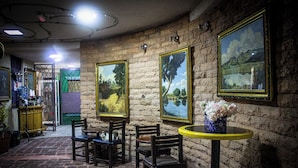 A room with brick walls, framed paintings, and a round table with a vase of flowers. - Habitación Doble Hotel Boutique Azul Turquesa (Cuernavaca)