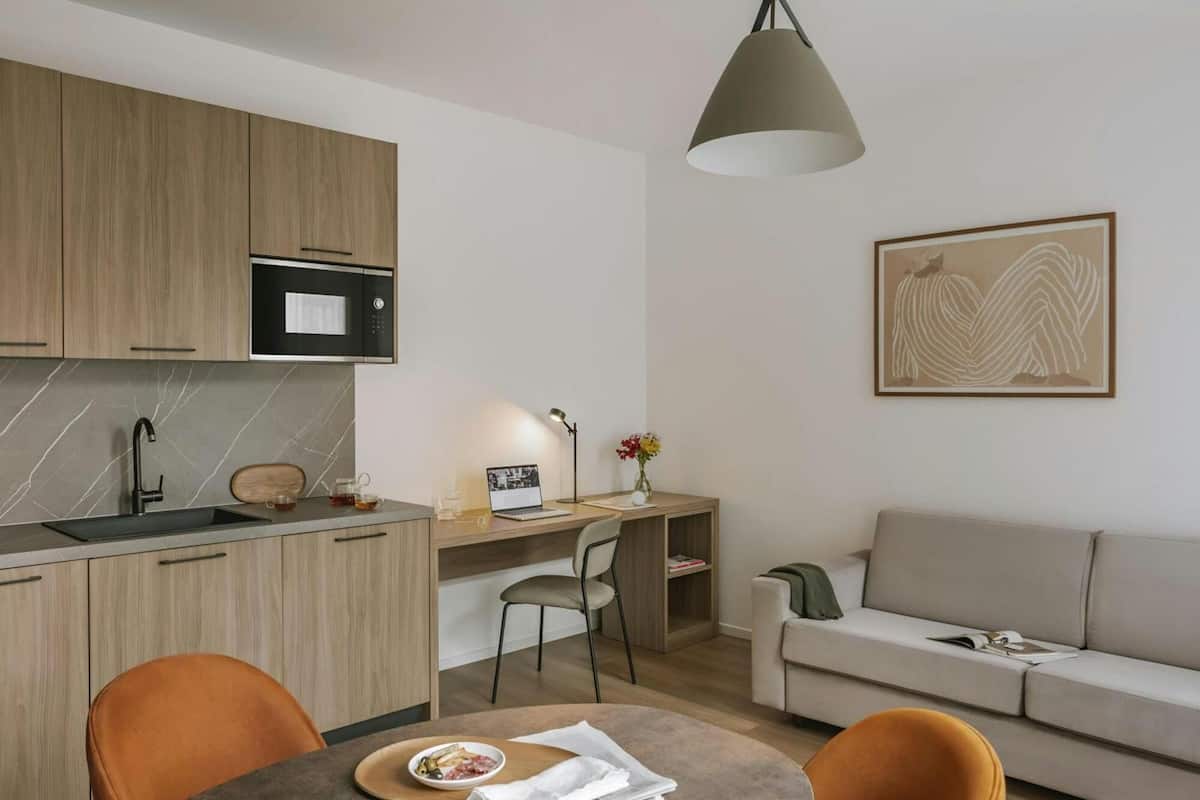 Una cocina moderna con microondas integrado, una mesa de comedor con sillas y un sofá en la sala.