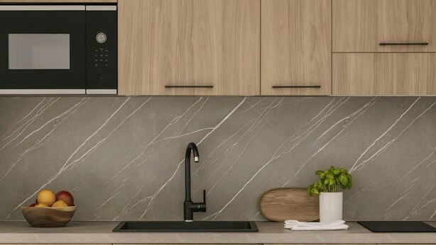 Una cucina moderna con armadietti in legno, forno a microonde integrato, schienale in marmo, lavello con rubinetto nero e zona pranzo con tavolo e sedie.
