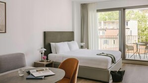 Camera d'albergo con un letto, una scrivania, una sedia, una lampada e vista all'esterno.