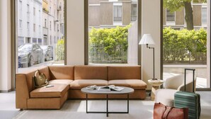 Ein modernes Wohnzimmer mit einer Eckcouch, einem runden Couchtisch und einer Stehlampe.