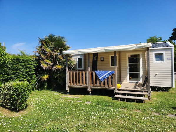 A small, single-story mobile home with a porch and a covered deck area. - Gildas - Confort 2 TV - 5p (4) (Préfailles)