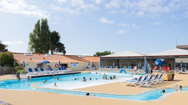 Uma área de piscina com várias piscinas, espreguiçadeiras e guarda-sóis.