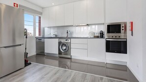 Una cocina moderna con electrodomésticos de acero inoxidable, lavadora integrada y microondas.