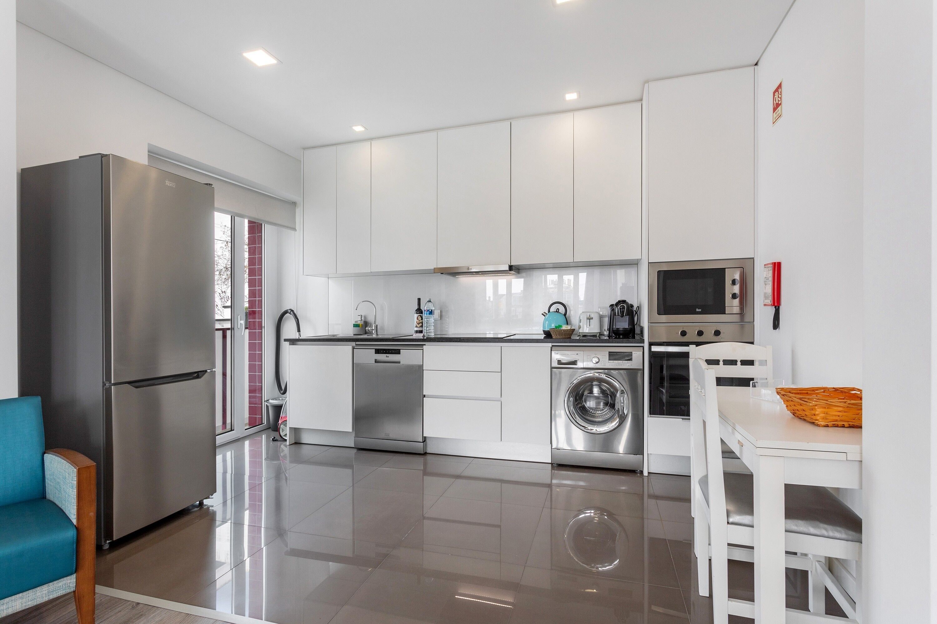 A modern kitchen with stainless steel appliances, a dishwasher, and a washing machine.