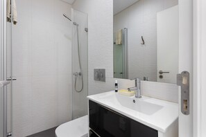 A modern bathroom with a glass shower enclosure, a white sink with a mirror, and a towel rack. - Apartment 'Dos Terraços T3 Rc' with Balcony, Wi-Fi and Air Conditioning (São Martinho do Porto)