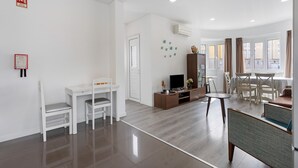 Una sala de estar moderna con televisor, asientos y comedor.