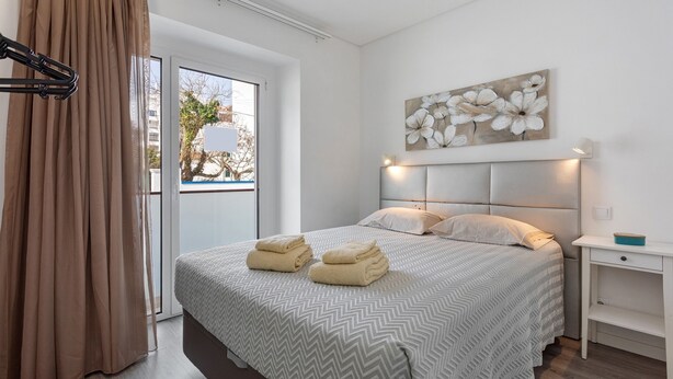 Una habitación de hotel con cama, mesita de noche, un cuadro y vistas por la ventana.