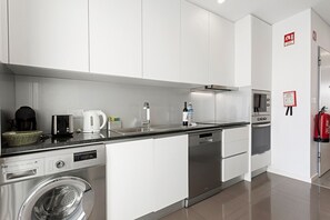 A modern kitchen with stainless steel appliances, a dishwasher, and a washing machine. - Apartment 'Casa Dos Terraços T2 1st' with Balcony, Wi-Fi and Air Conditioning (São Martinho do Porto)