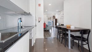 Una cocina moderna con un lavamanos de acero inoxidable, dispensador de agua y un comedor con mesa y sillas.