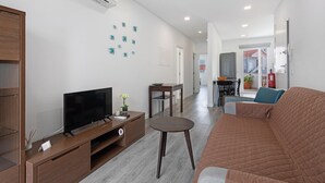 Una sala de estar moderna con una televisión de pantalla plana, un mueble de entretenimiento de madera, una mesa de centro redonda y un sofá marrón.