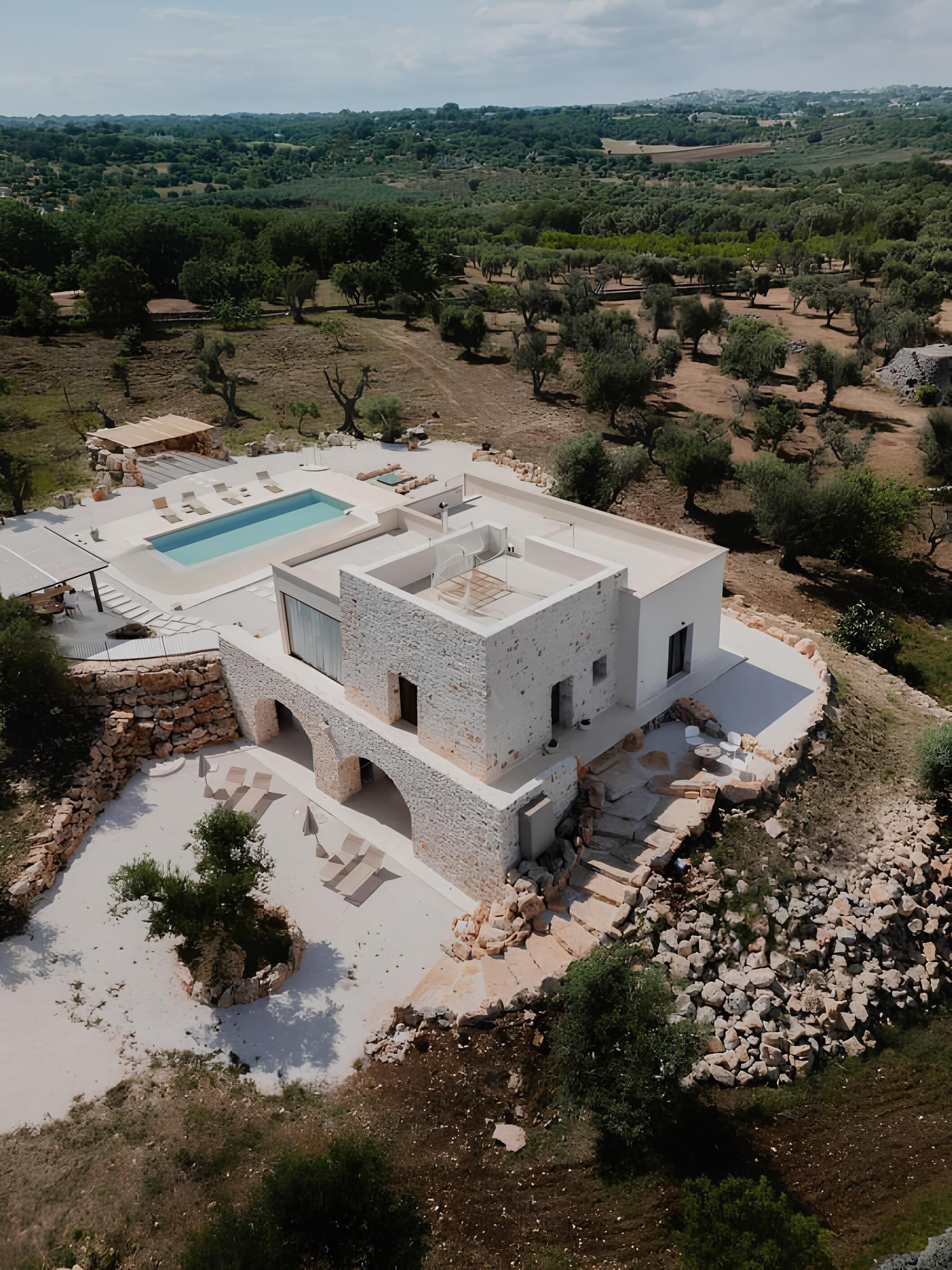 Eine moderne Villa mit Swimmingpool, Steinarchitektur und Blick auf die umliegende Landschaft.