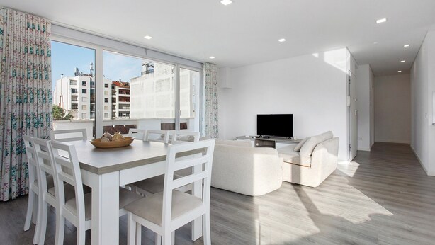 A modern living room with a dining area, a flat-screen TV, and large windows. - Apartment 'Casa Dos Terraços Penthouse' with Balcony, Wi-Fi and Air Conditioning (São Martinho do Porto)