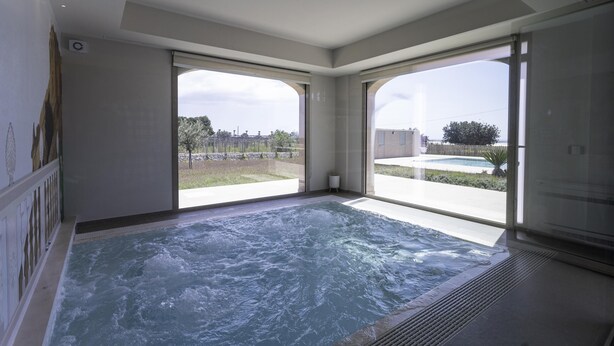 Een moderne, overdekte jacuzzi met grote ramen die uitzicht bieden op de omgeving.