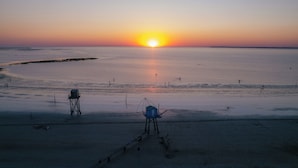 Une plage au coucher du soleil, avec une tour de surveillance et un poste de sauveteur.