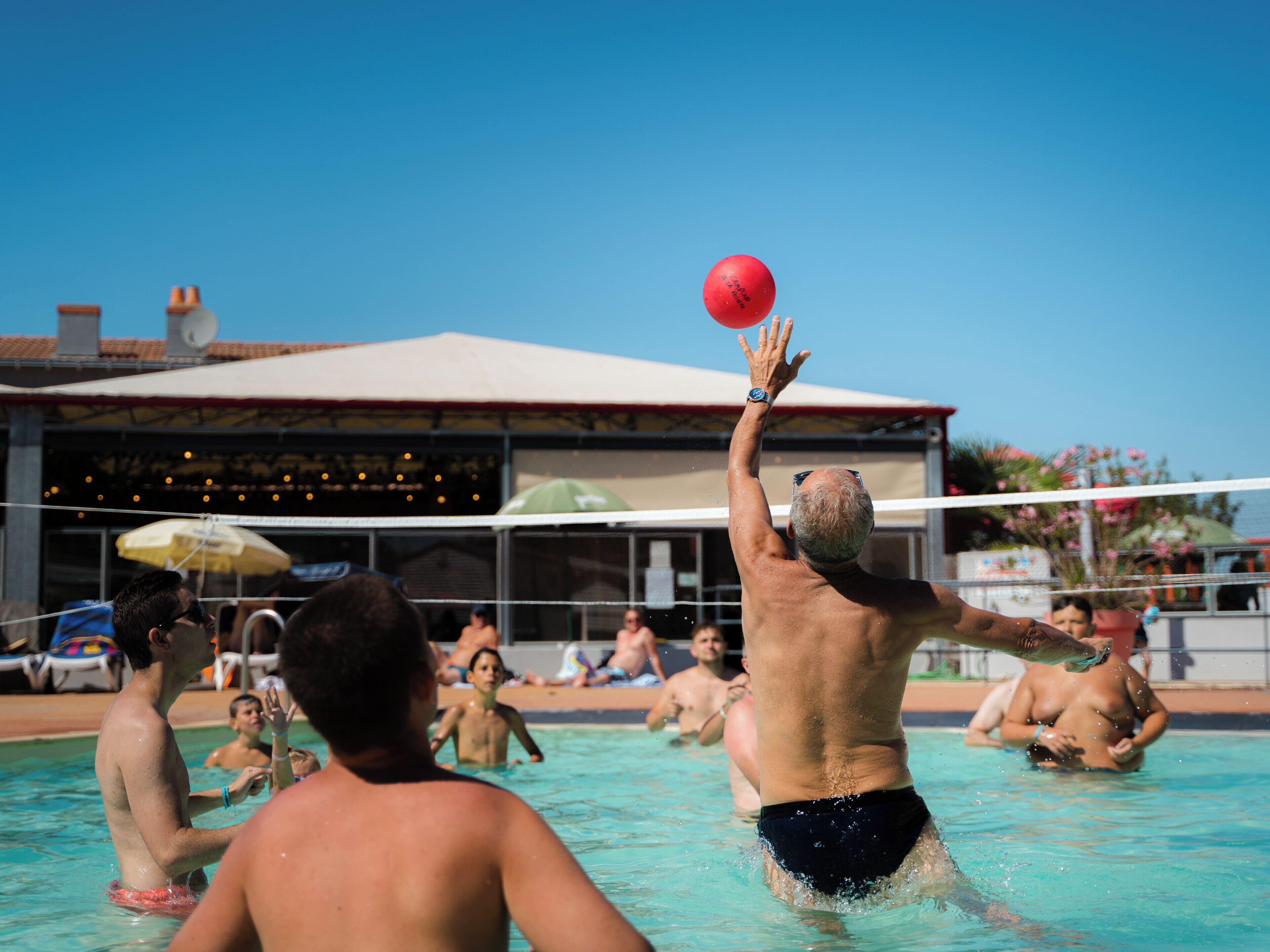 Een zwembad waar mensen volleybal spelen.