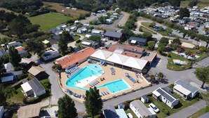 Vista aérea de um bairro residencial com uma grande piscina cercada por espreguiçadeiras e um pavilhão coberto.