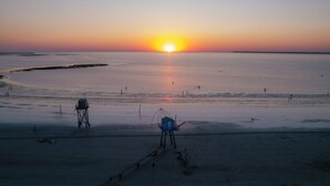 Uma praia ao pôr do sol com uma torre salva-vidas e um posto de salva-vidas.