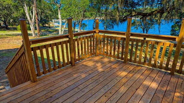 A wooden deck with a railing overlooking a body of water. - Cozy 1-bedroom lake front cabin in the quaint town of Keystone Heights, FL (Keystone Heights)