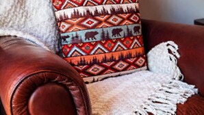 A leather armchair with a patterned throw pillow and a fringed throw blanket. - Cozy 1-bedroom lake front cabin in the quaint town of Keystone Heights, FL (Keystone Heights)
