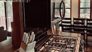 Une cuisine avec des meubles de rangement en bois, une cuisinière à gaz, un four à micro-ondes et un bloc à couteaux.
