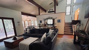 Un salon spacieux, avec un canapé aux couleurs sombres, une table basse en bois et un escalier menant à un niveau supérieur.