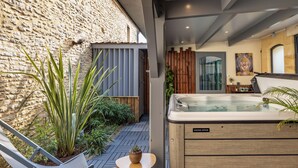 A spa area with a hot tub, seating, and plants. - Truffe - Chalet confort 2 – 5p (2) (Saint-Geniès)