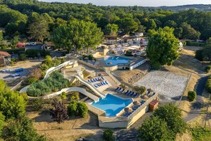 Ein Luftbild zeigt ein Resort mit einem Schwimmbad, Liegebereichen und einer überdachten Terrasse.