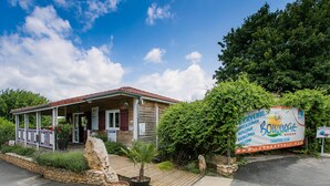 A small building with a porch, a signboard, and a stone wall. - Truffe - Chalet confort 3 – 6p (8) (Saint-Geniès)