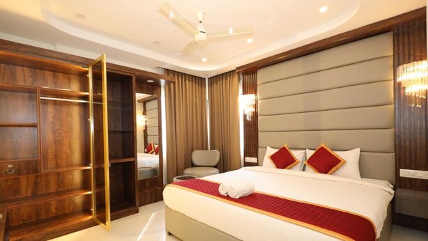 Une chambre d’hôtel spacieuse, dotée d’un grand lit, d’une armoire en bois, d’un coin salon et d’un ventilateur de plafond.