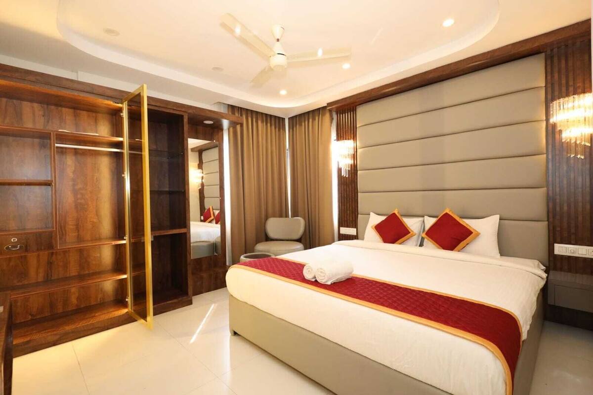 Un'ampia camera d'albergo con un letto grande, un armadio in legno, un'area salotto e una ventola a soffitto.