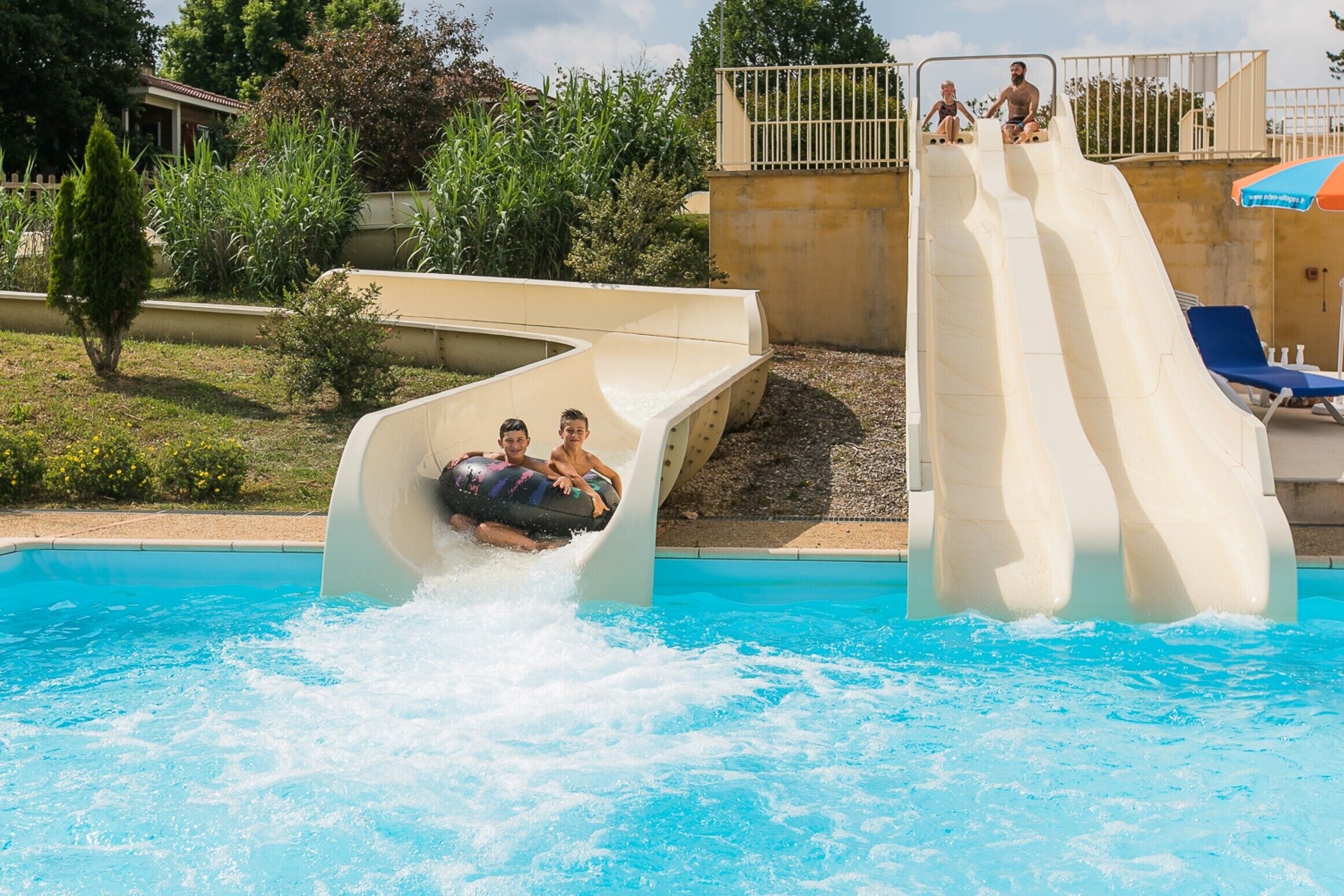 Une piscine avec un toboggan et des chaises longues.