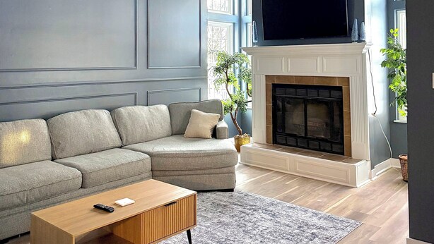 A living room with a grey sofa, a wooden coffee table, a fireplace, and a ceiling fan.