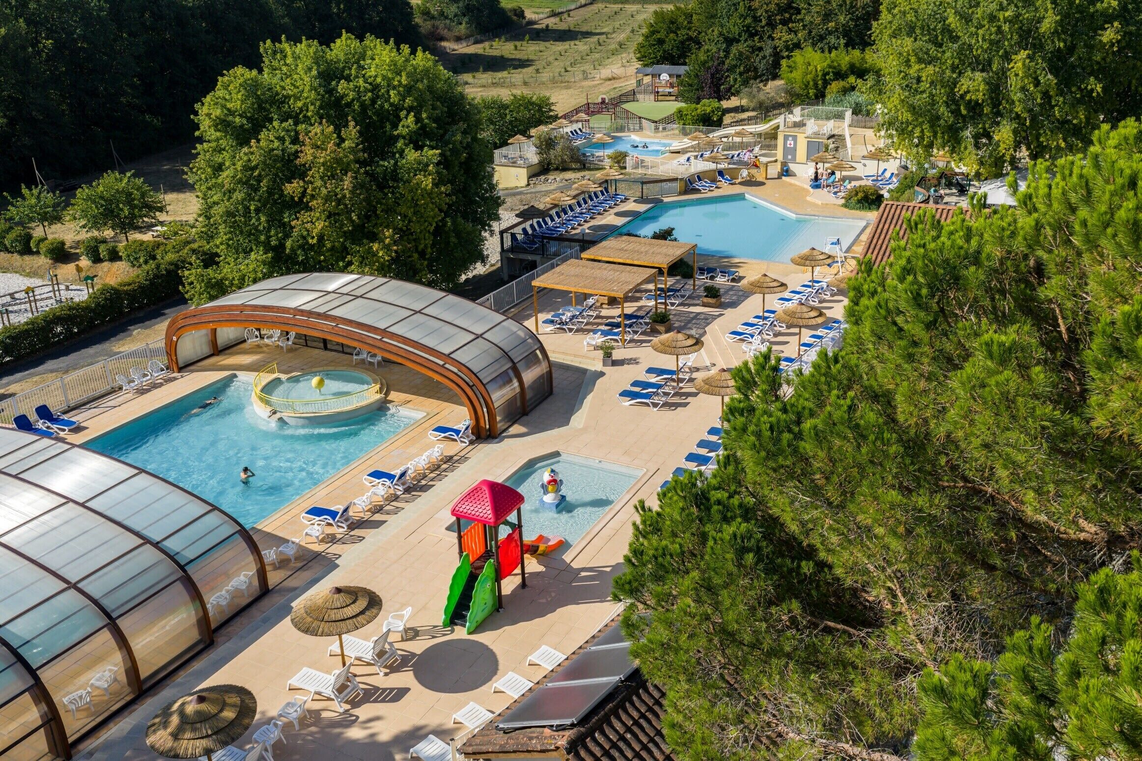 Et resort med flere swimmingpools, liggestole og et overdækket område.