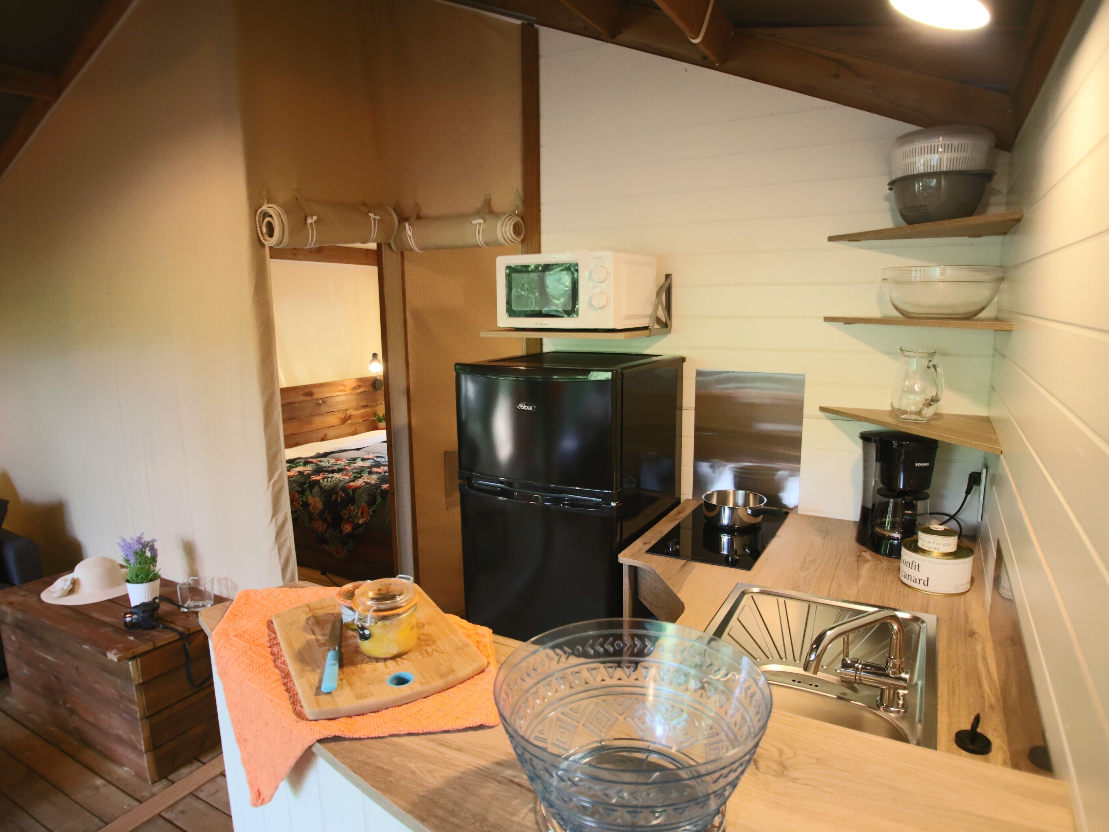 A compact kitchen with a refrigerator, microwave, coffee maker, and a sink.