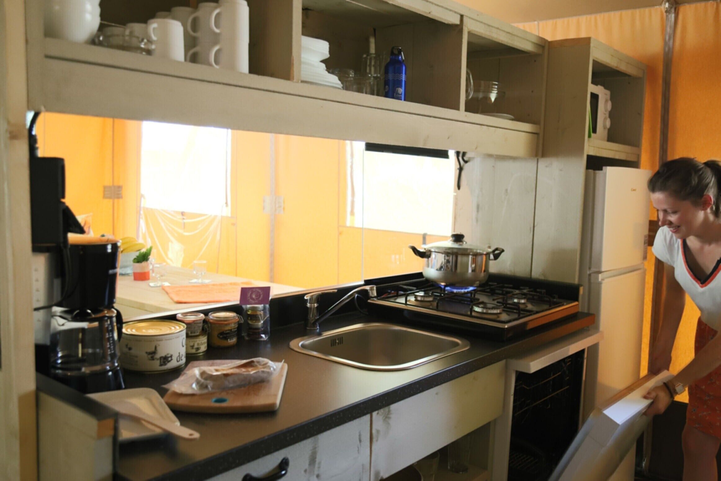 Una cocina con estufa, pileta y armarios. Se ve a una persona abriendo un armario.