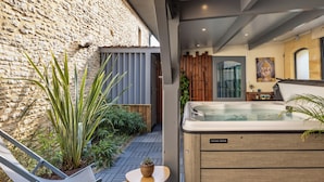 Een wellnessruimte met een whirlpool, zitplaatsen en planten.