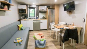 A compact living space with a kitchenette, a dining area, and a sofa. - Truffe - Privilège 2 - 4p (2) (Saint-Geniès)