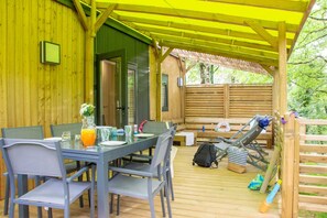 A wooden deck with a table and chairs, a bench, and a covered area with a yellow roof. - Truffe - Privilège 2 - 4p (4) (Saint-Geniès)