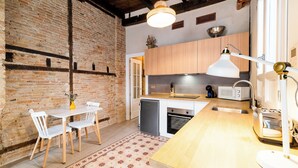 Une cuisine dotée d’un plan de travail en bois, de meubles blancs, d’un four encastré et d’un four à micro-ondes.