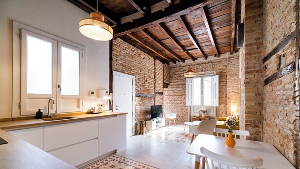 Une cuisine avec des armoires blanches, un plan de travail en bois et un luminaire suspendu.