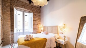 Une chambre d’hôtel avec un lit, une table de chevet, un miroir et une fenêtre donnant sur un paysage agréable.