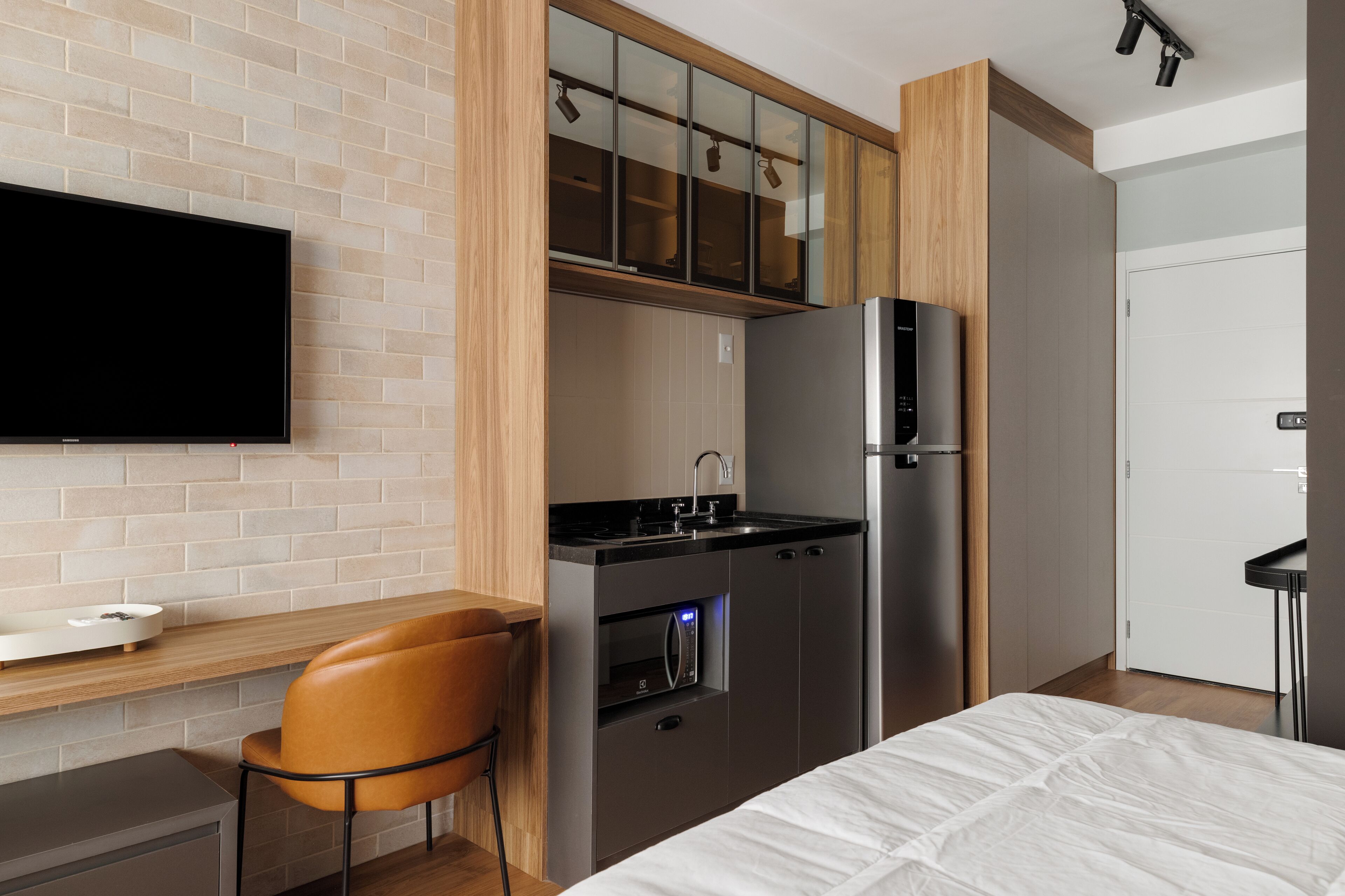 Una cocina moderna con horno empotrado, refrigerador y televisor de pantalla plana montado en la pared.